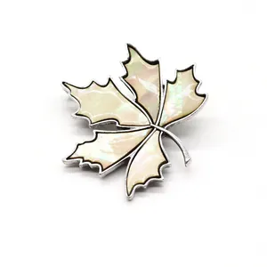 Gros plan détaillé d'une broche en feuille d'érable avec nacre irisée et cadre argenté