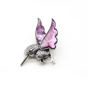 Détail macro de la broche colibri avec nacre violette et textures métalliques