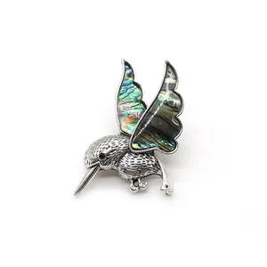 Vue macro d'une broche colibri en argent vintage incrustée d'une nacre d'abalone irisée