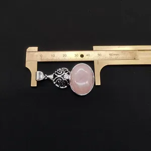 Close-up of pink quartz gourd pendant measured with caliper for sizing details