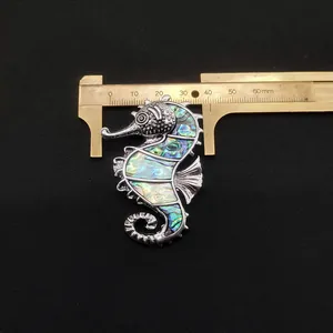 Macro shot of seahorse brooch measuring 50mm height with iridescent abalone shell inlay