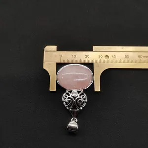 Detailed macro view showing the 24mm rose quartz stone width measured with a brass caliper