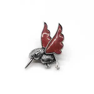 Détail de la broche colibri avec ailes rouges et plumes argentées finement gravées