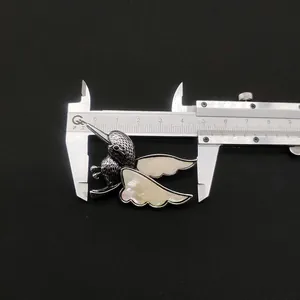 Détail de la broche colibri en nacre montrant une largeur de 45 mm sur un pied à coulisse