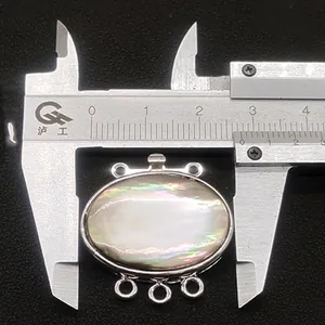 Macro shot of oval shell pendant with three loops measured by caliper for DIY jewelry