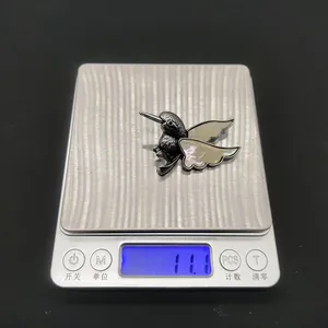 Détail de la broche colibri en nacre affichant un poids de 11,1g sur une balance