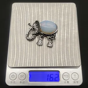 Detailed weight display of vintage elephant brooch with natural stone inlay on scale