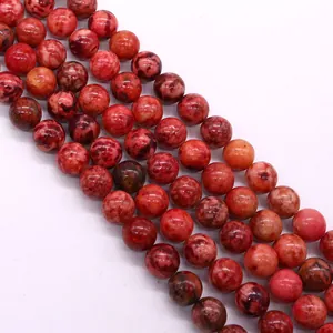 Dettaglio macro di perle tonde in pietra imperiale con venature rosse per gioielli fai da te