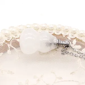 Dettaglio macro del ciondolo a boccetta di profumo in cristallo bianco e catena