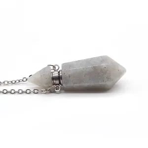 Close-up of natural hexagonal stone perfume bottle necklace with silver chain on white background