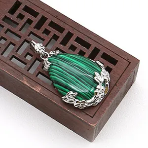 Dettaglio macro del ciondolo in malachite a goccia con intagli floreali in argento