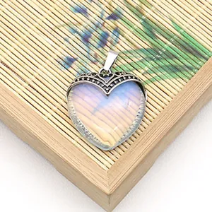 Macro-opname van hartvormige opaliet hanger met vintage metalen rand op bamboe