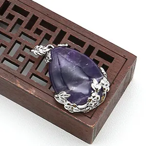 Dettaglio del ciondolo in cristallo viola a goccia con cornice floreale in argento