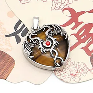 Macro view of heart-shaped tiger eye stone pendant with silver metal dragon and red gem