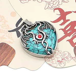 Macro shot of gothic heart pendant with green turquoise stone, silver dragon, and red gem
