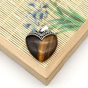 Macro-opname van hartvormige tijgeroog hanger met vintage holle zilveren sluiting