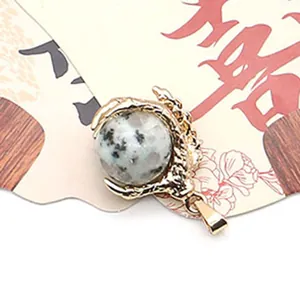 Detailed view of a golden dragon claw pendant holding a spotted natural stone bead
