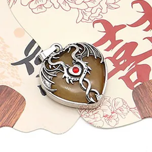 Close-up of a heart-shaped spotted stone pendant with a silver dragon wrap and red gem