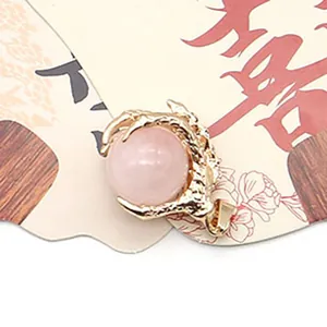 Macro view of gold dragon claw pendant holding a pink quartz stone on display card