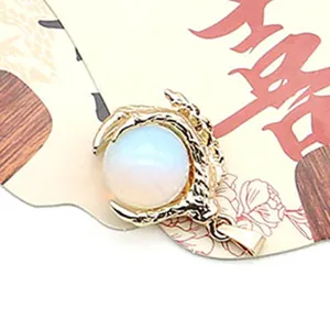 Close-up of a golden dragon claw pendant holding a white round natural stone bead
