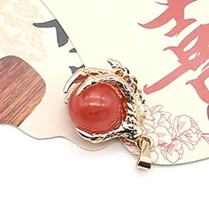 Macro shot of gold dragon claw pendant holding a round red stone with detailed clasp