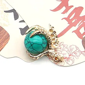 Macro detail of turquoise gemstone bead held by a golden dragon claw jewelry pendant