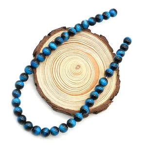 Dettaglio di perline tonde occhio di tigre blu con trama lucida su base legno