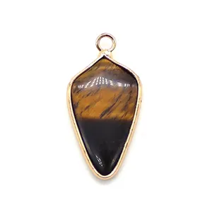 Macro detail of shield-shaped tiger eye stone pendant with polished golden metal frame