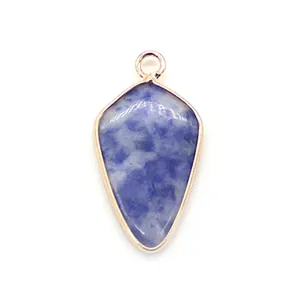 Macro detail of blue stone shield pendant with a gold plated metal frame and top bail