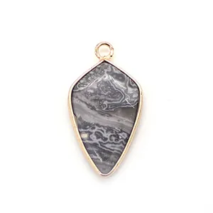 Macro detail of natural stone shield pendant with golden metal border for DIY jewelry