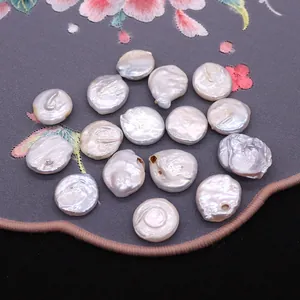 Perle naturali barocche bianche lucide disposte su un elegante tessuto di seta ricamato
