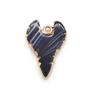 Detalle del colgante de ágata en forma de corazón con bordes chapados en oro y textura de piedra