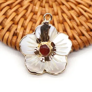 Vue macro d'un pendentif fleur avec pétales en nacre blanche et pierre centrale rouge