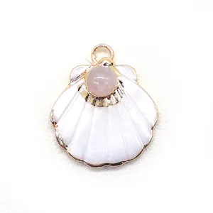 Close-up of shell-shaped jewelry pendant with white inlay and pink stone set in gold frame