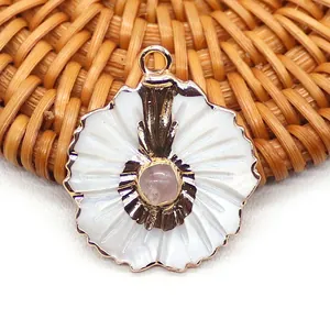 Détail macro d'un pendentif fleur en or avec pétales en nacre blanche et pierre rose