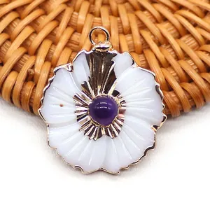 Vue macro d'un pendentif fleur doré avec pétales en coquillage blanc et pierre violette