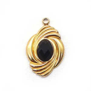 Macro detail of gold oval pendant with black gemstone and vintage twisted texture