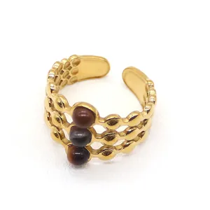 Close-up of Egyptian style 18K gold ring with multi-layer dot texture and tiger eye stones