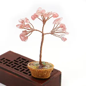 Detalle de un árbol de cristal rosa hecho a mano con hilo de cobre en una cesta tejida