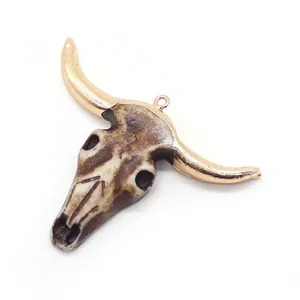 Detailed view of resin bull skull pendant with metallic rose gold electroplated horns