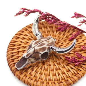Detailed close-up of retro resin bull skull pendant with silver horns on a woven mat