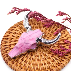 Detailed view of pink resin bull skull pendant with silver plated metal edges and loop