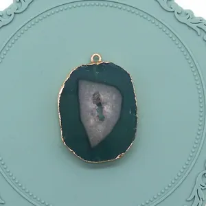 Vue détaillée du pendentif en agate verte avec bord doré sur un plateau décoratif
