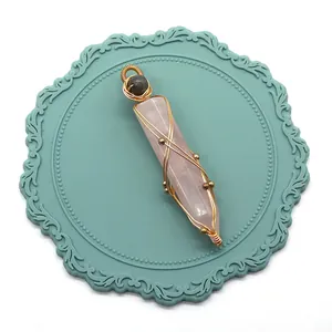Détail du pendentif quartz rose avec fil doré sur un dessous de verre bleu sarcelle