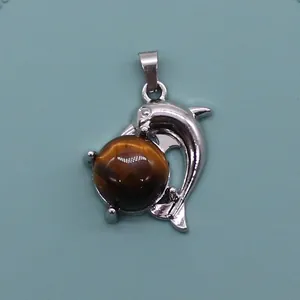 Detailed close-up of a silver dolphin pendant featuring a natural tiger eye stone ball