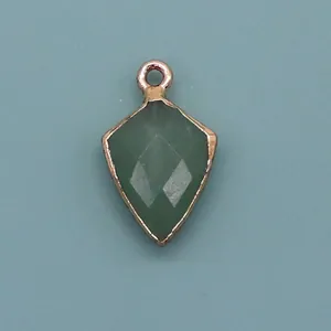 Macro detail of a shield-shaped green natural stone pendant with gold plated edges