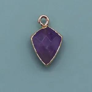 Detailed macro view of faceted purple gemstone shield pendant with a gold plated edge
