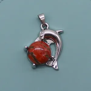 Detail of silver dolphin pendant with natural red stone bead and polished finish