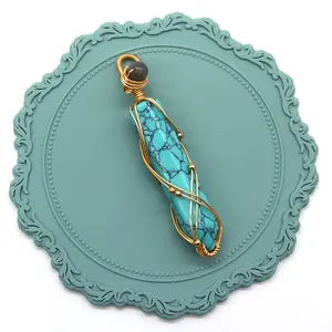 Vue détaillée d'un pendentif hexagonal en turquoise enroulé de fil doré sur un support bleu