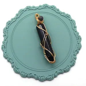 Détail d'un pendentif en onyx noir enveloppé de fil doré fait à la main pour collier